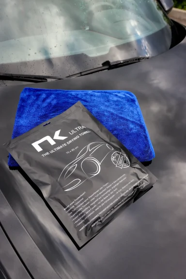 NK-ULTRA Autotrockentuch mit Verpackung auf Autolack – hochwertiges Mikrofasertuch für streifenfreie Fahrzeugpflege